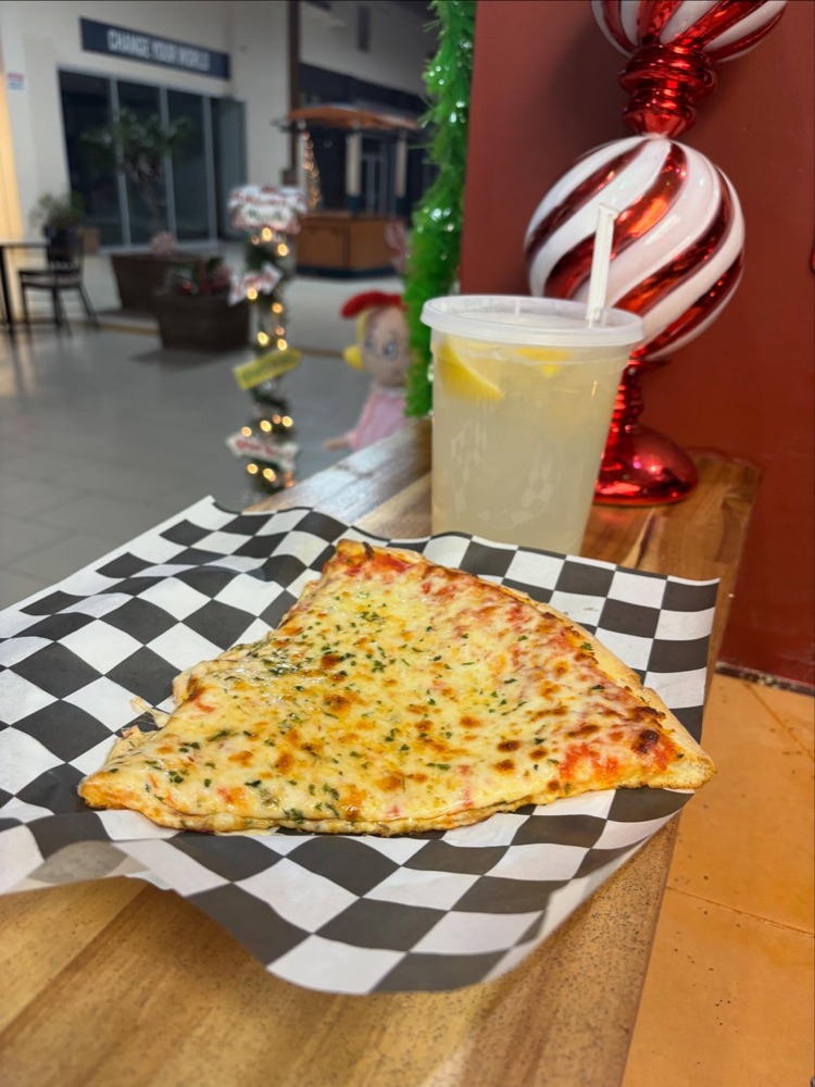 A fresh New York–style cheese slice on checkered paper
