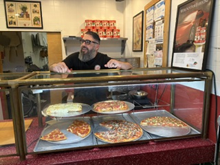 An employee behind the pizza display case